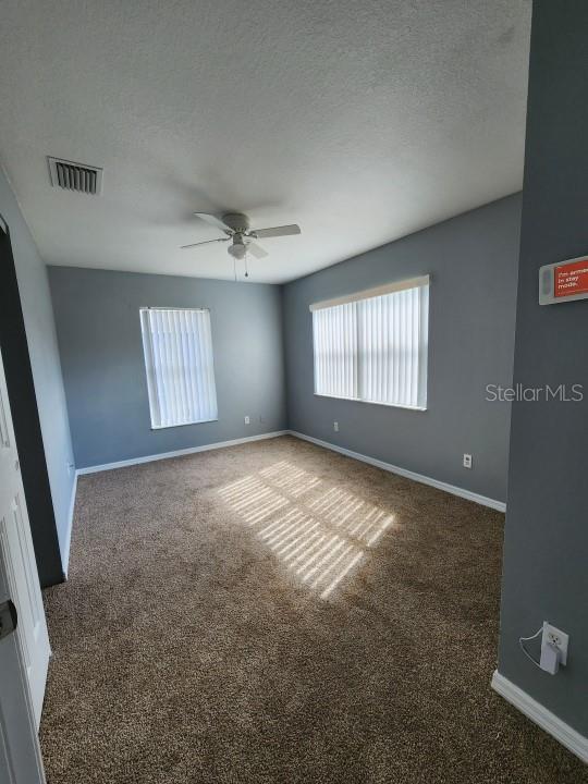 carpeted empty room with ceiling fan and a textured ceiling