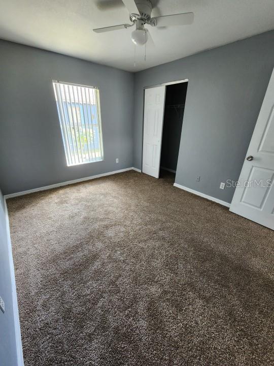 unfurnished bedroom with ceiling fan, a closet, and carpet