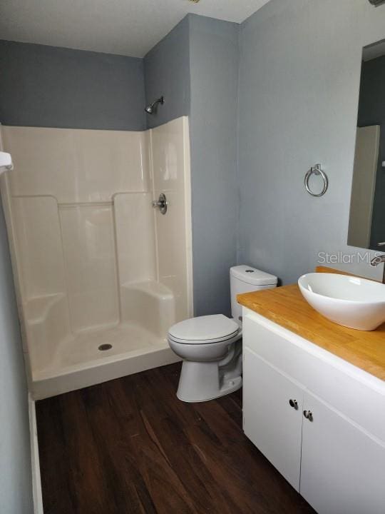 bathroom featuring wood-type flooring, a shower, vanity, and toilet