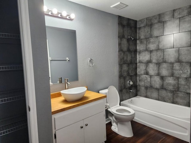 full bathroom featuring vanity, hardwood / wood-style floors, toilet, and tiled shower / bath