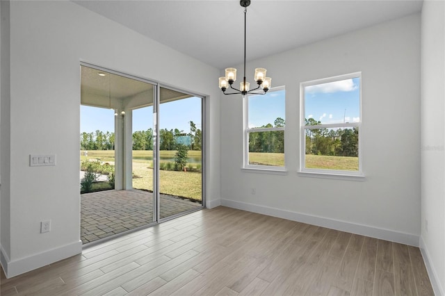 unfurnished room with hardwood / wood-style floors and an inviting chandelier