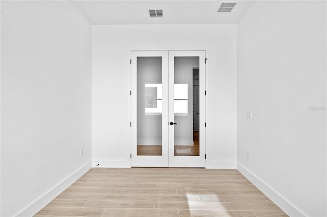 spare room featuring french doors and light wood-type flooring