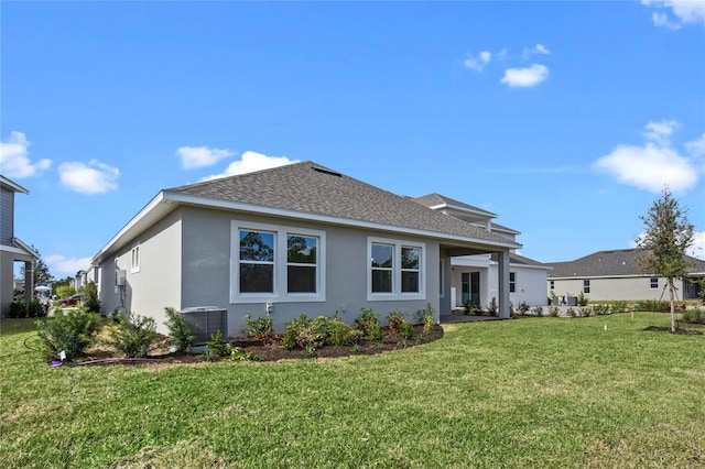 rear view of house featuring a lawn and central AC unit