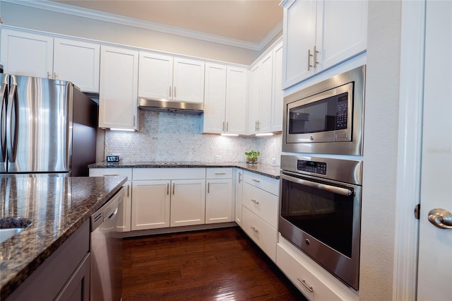 kitchen with dark hardwood / wood-style flooring, stainless steel appliances, crown molding, dark stone countertops, and white cabinetry