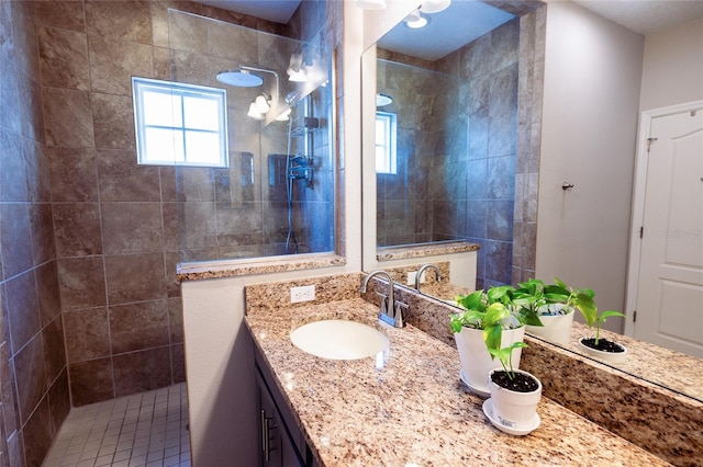 bathroom with a tile shower and vanity