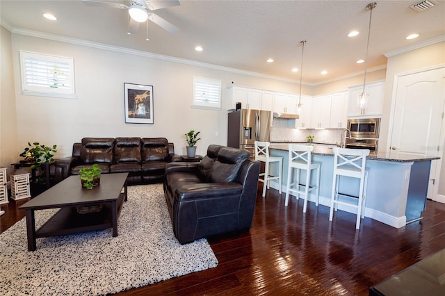 living room with dark hardwood / wood-style floors, ceiling fan, ornamental molding, and a textured ceiling