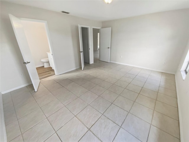 unfurnished bedroom with ensuite bath and light tile patterned floors