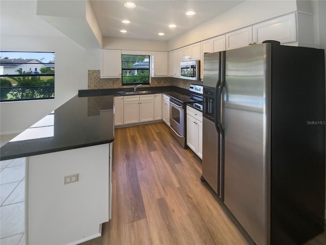 kitchen featuring backsplash, stainless steel appliances, sink, wood-type flooring, and white cabinets