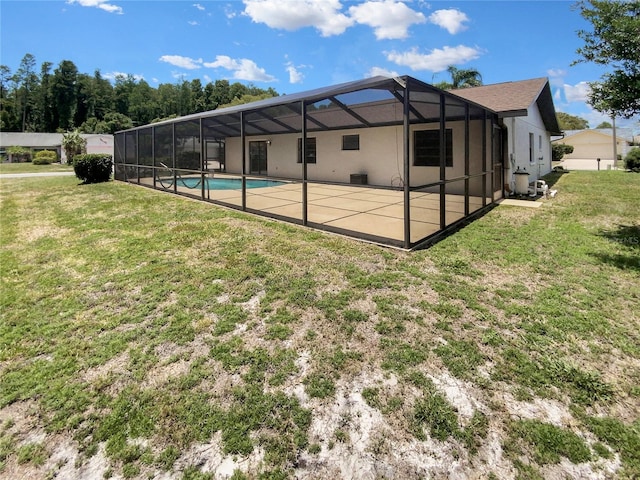 back of property featuring glass enclosure, a patio area, a fenced in pool, and a yard