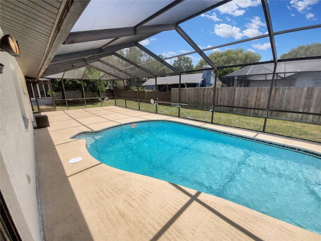 view of pool featuring a lawn, glass enclosure, and a patio