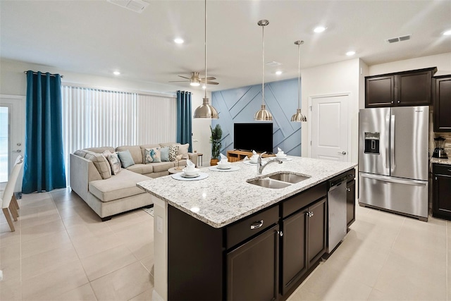 kitchen with light stone countertops, ceiling fan, sink, a kitchen island with sink, and appliances with stainless steel finishes