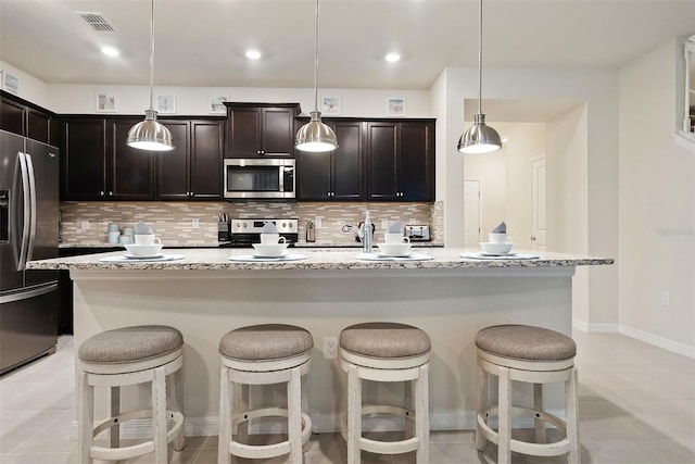 kitchen with stainless steel appliances, decorative light fixtures, and light tile floors