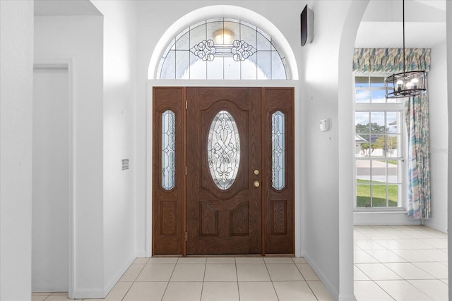 tiled foyer entrance with an inviting chandelier