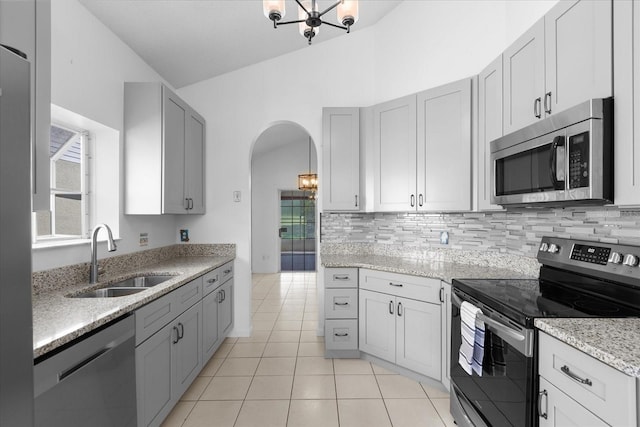 kitchen featuring backsplash, stainless steel appliances, sink, light tile patterned floors, and an inviting chandelier