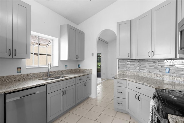 kitchen featuring light tile patterned floors, tasteful backsplash, stainless steel appliances, gray cabinetry, and a sink