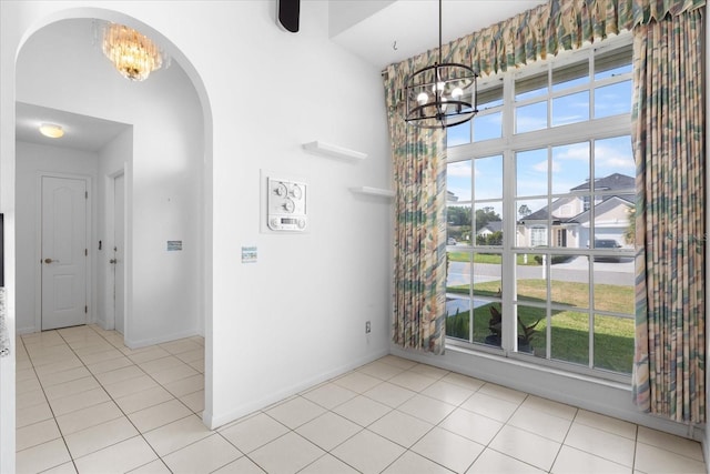 unfurnished dining area featuring an inviting chandelier, a healthy amount of sunlight, and light tile patterned flooring