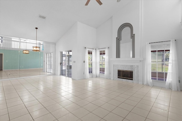 unfurnished living room with ceiling fan, a fireplace, high vaulted ceiling, and light tile patterned floors