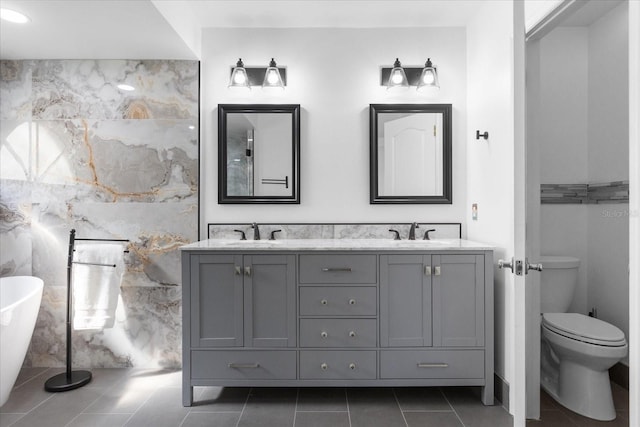 full bath with double vanity, a sink, toilet, and tile patterned floors