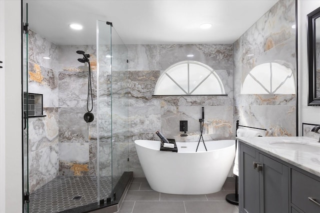 bathroom with separate shower and tub, tile patterned flooring, vanity, and tile walls