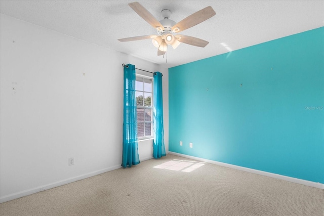 unfurnished room featuring baseboards, ceiling fan, a textured ceiling, and light colored carpet