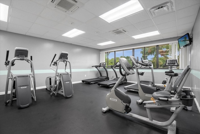 gym featuring a paneled ceiling, visible vents, and baseboards