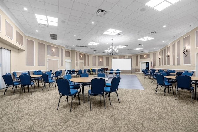 dining space featuring a drop ceiling, light carpet, and an inviting chandelier