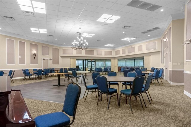 dining area with a paneled ceiling, a notable chandelier, and light colored carpet