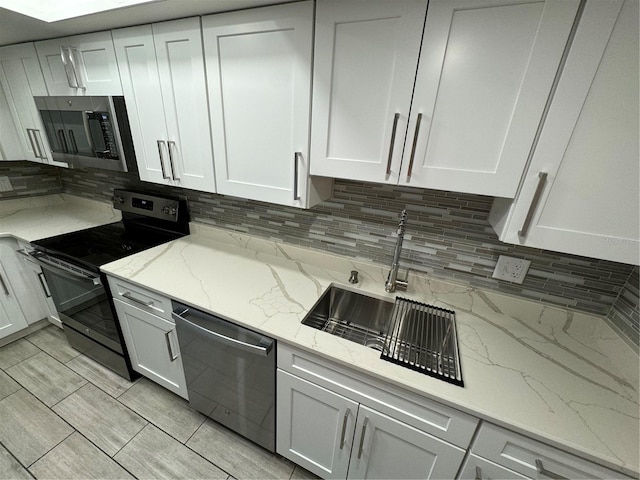 kitchen featuring light stone countertops, backsplash, stainless steel appliances, and white cabinets