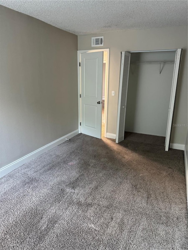 unfurnished bedroom featuring a closet, a textured ceiling, and dark colored carpet