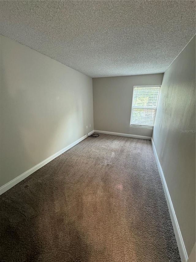 carpeted empty room featuring a textured ceiling