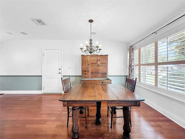 dining area featuring an inviting chandelier, lofted ceiling, and dark hardwood / wood-style flooring