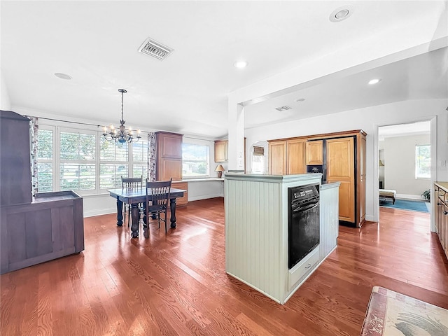 kitchen featuring a center island, a notable chandelier, dark wood-type flooring, and pendant lighting