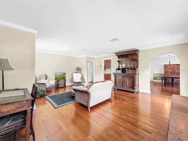 living room featuring crown molding, hardwood / wood-style flooring, and a notable chandelier