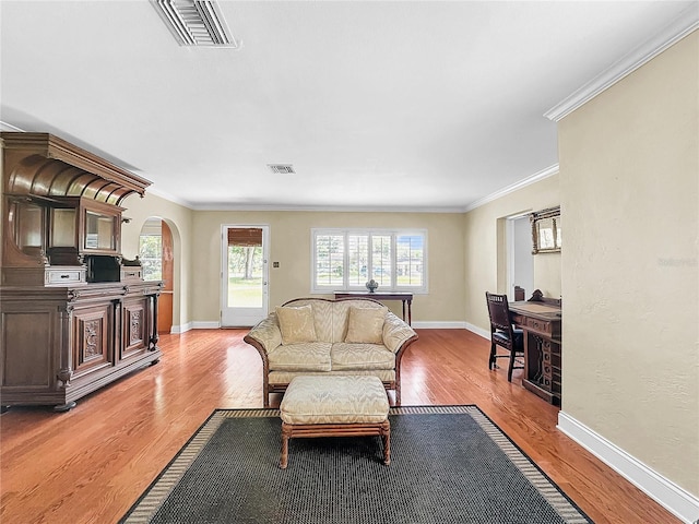 living room featuring light hardwood / wood-style flooring, crown molding, and a wealth of natural light