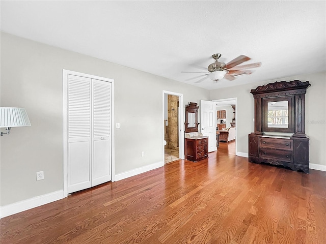 unfurnished bedroom with a closet, ceiling fan, connected bathroom, and hardwood / wood-style flooring