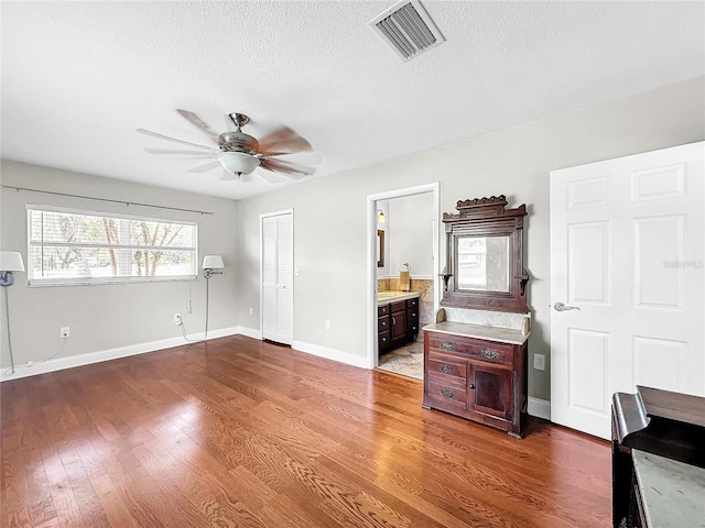 living room featuring ceiling fan, hardwood / wood-style flooring, and a textured ceiling