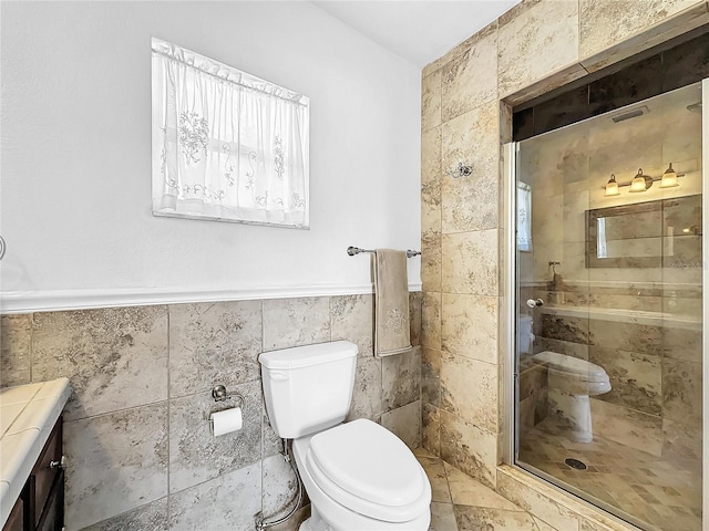 bathroom with a shower with door, vanity, toilet, and tile walls