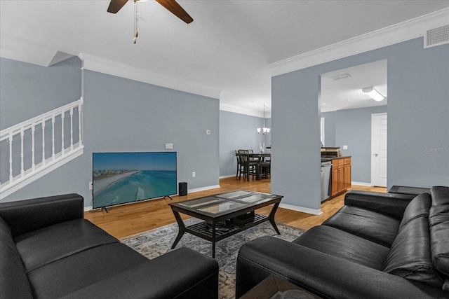 living room featuring ceiling fan with notable chandelier, light hardwood / wood-style floors, and ornamental molding