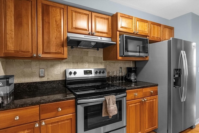 kitchen featuring decorative backsplash, dark stone countertops, and appliances with stainless steel finishes