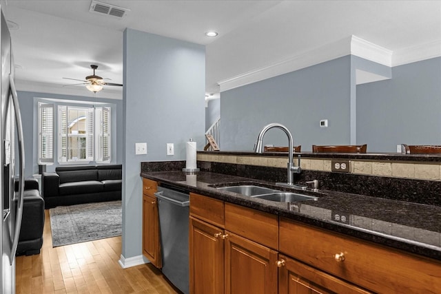 kitchen featuring dark stone countertops, sink, appliances with stainless steel finishes, and light hardwood / wood-style flooring