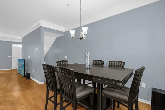 dining area featuring crown molding, a notable chandelier, and hardwood / wood-style flooring