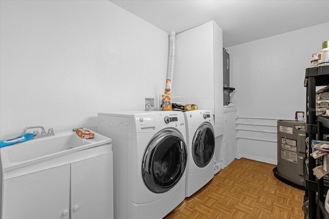 laundry area with cabinets, electric water heater, sink, separate washer and dryer, and light parquet flooring