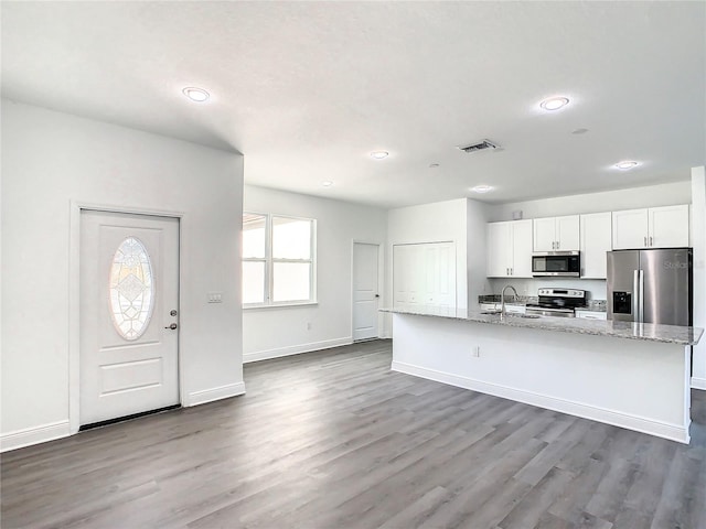 kitchen featuring white cabinets, a center island with sink, sink, dark hardwood / wood-style floors, and appliances with stainless steel finishes