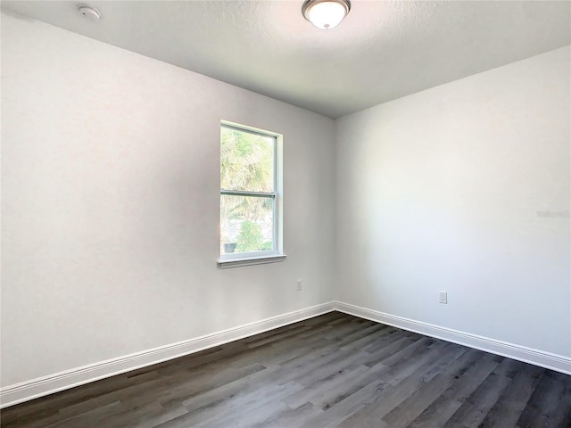 unfurnished room with dark wood-type flooring