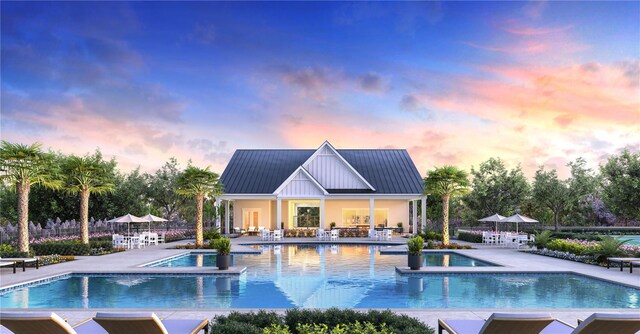 pool at dusk featuring a patio area and an in ground hot tub