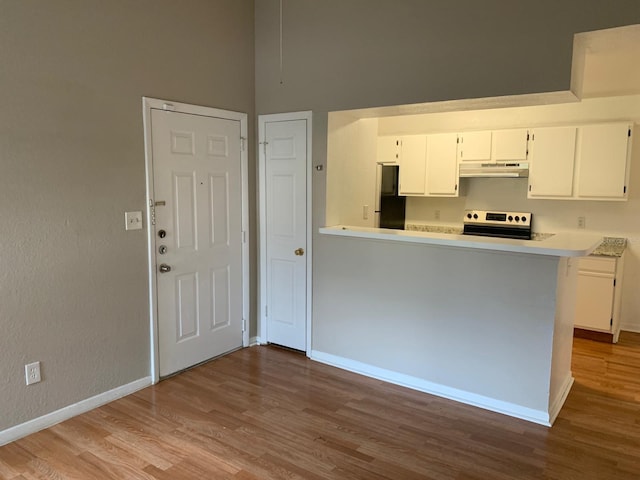 kitchen featuring kitchen peninsula, black refrigerator, light hardwood / wood-style flooring, white cabinets, and range with electric stovetop