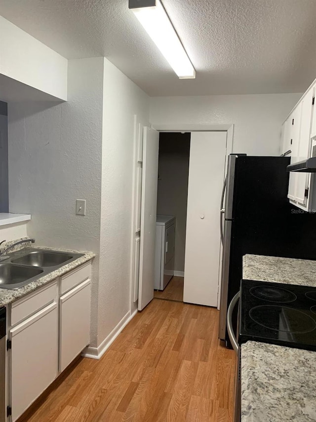 kitchen featuring white cabinets, sink, light hardwood / wood-style flooring, a textured ceiling, and washer / dryer