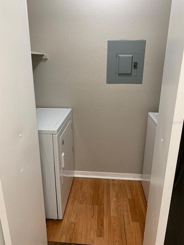 washroom with electric panel, light hardwood / wood-style flooring, and washer and dryer