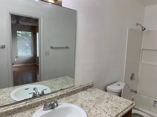 full bathroom featuring hardwood / wood-style floors, vanity, toilet, and bathtub / shower combination