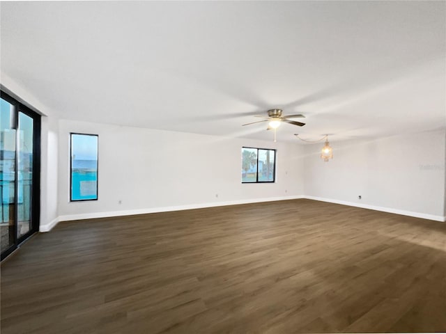 empty room with dark wood-type flooring, ceiling fan, and baseboards